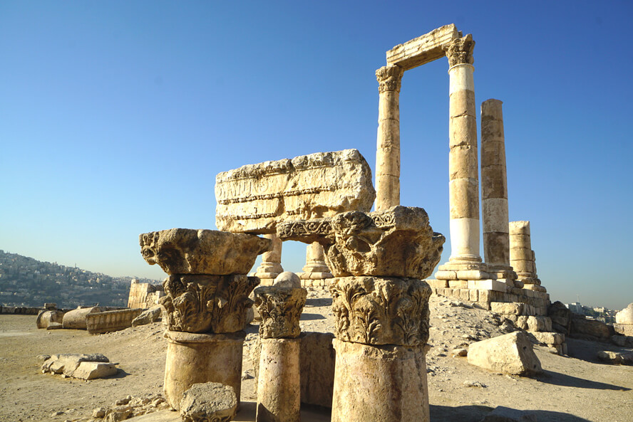 Roman columns, in ruins, sit on a hill above the city of Amman: The Ancient Cities, Vast Deserts, and Salty Seas of Jordan