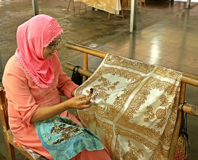 Woman drawing Batik on fabric | Location: Indonesia