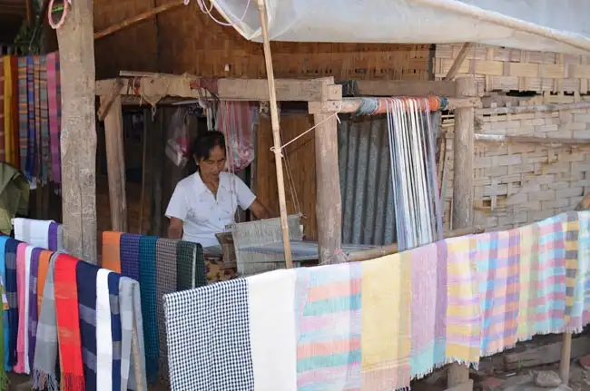 Lao woman is weaving traditional textiles on wooden frame loom | Location: Luang Prabang,  Laos